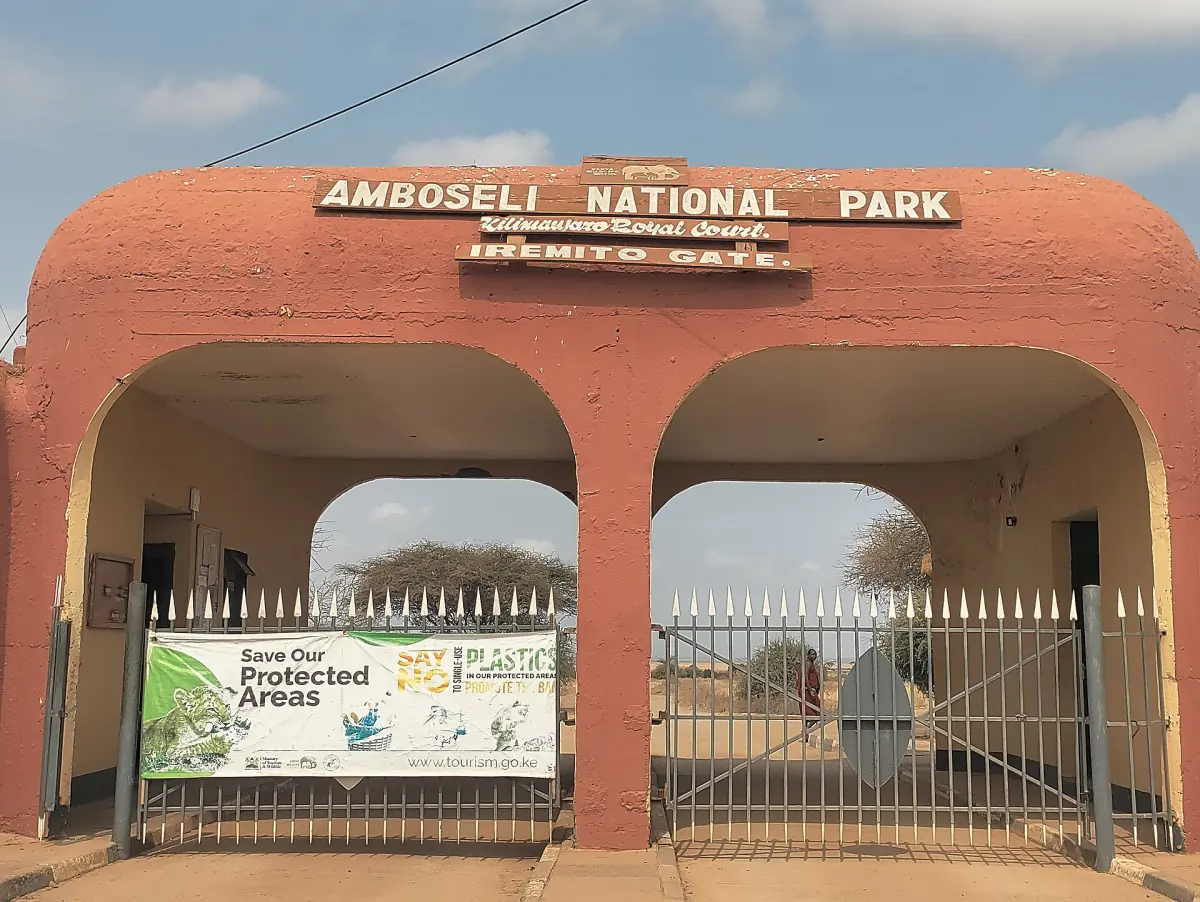 Red clay coloured entrance gate with arches and the Amboseli National Park sign