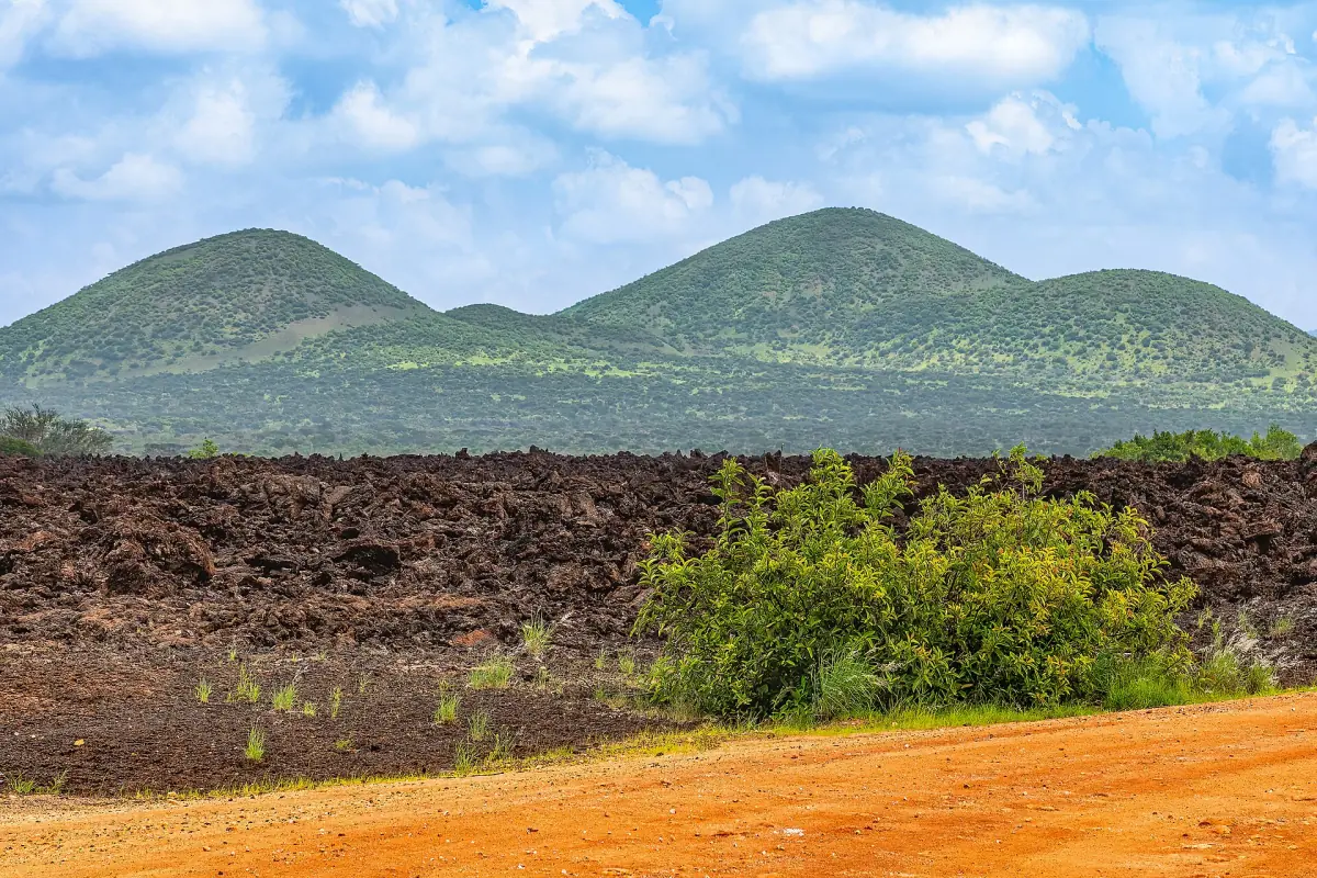 Rounded green Chyulu Hills peaks rising above dark volcanic rock