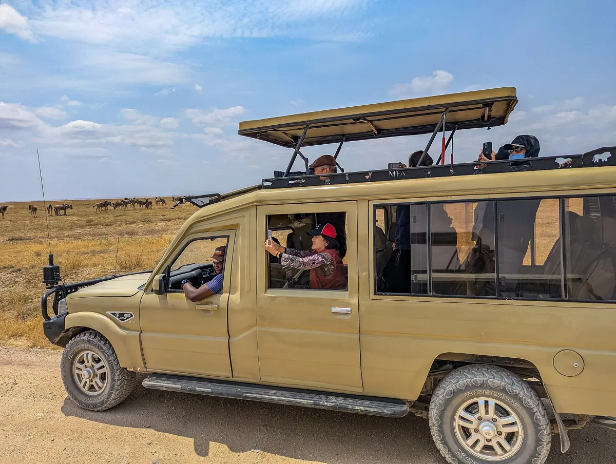 Tan safari truck with a pop-up roof standing on a dirt road